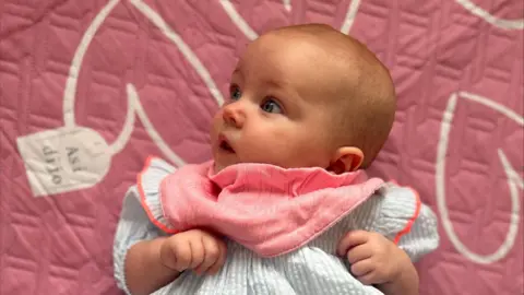 Handout Baby in a blue and pink dress.