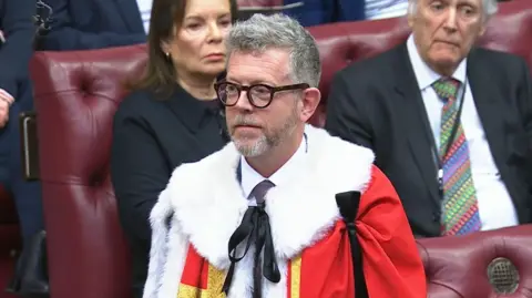 UK Parliament Lord Doyle is introduced to the House of Lords in January 2026. He is wearing a ceremonial red robe with a white fur collar.