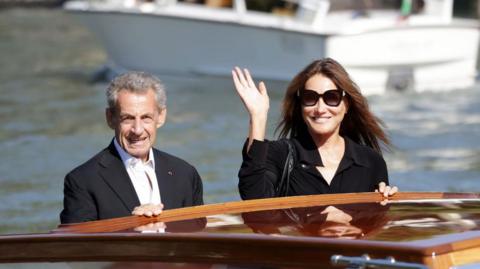 Nicolas Sarkozy and Carla Bruni-Sarkozy waving from a boat