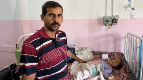Father with child with drips on hospital bed