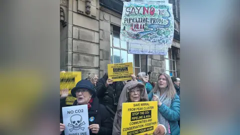 Protesters outside Wallasey Town Hall hold up signs opposing the Peak Cluster scheme. One reads: 'Say no to pipeline from hell' 