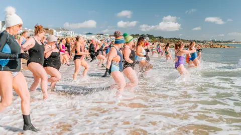 Land and Sea Hundreds of women in swimming costumes run into the sea at Sandbanks