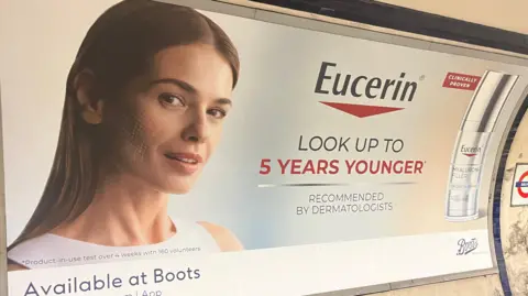 Eucerin's billboard advert showing a woman with dots highlighting her cheek, with the words 'look up to 5 years younger' and 'recommended by dermatologists', with an image of the silver and transparent bottle, next to the words 'clinically proven' in a red box.