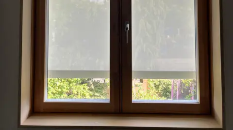 Catherine Katzka A white blind on the outside of a window in a house.