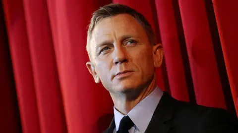 Daniel Craig pictured on the red carpet for the James Bond film Spectre; he is wearing a black suit.