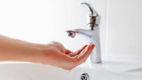 Water running from a tap onto a hand
