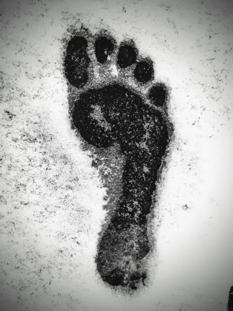 Mick Bennett A monochrome picture of a man's bare footprint in snow.