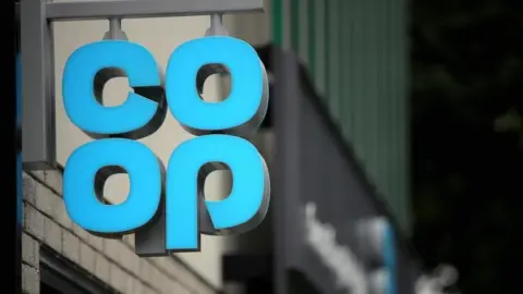A hanging sign outside a shop showing the pale blue Co-op logo