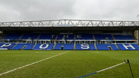 Emma Baugh/BBC Lapangan sepak bola kosong dan kata -kata 'The Posh' dapat dilihat di kursi di dudukan yang berlawanan.