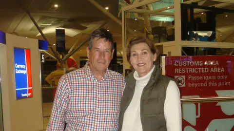 Margaret Murphy A man with a plaid top and grey hair and a woman with brown hair wearing a cream jumper and a green gilet.