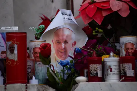 Getty Images Tributes of flowers, images, candles, and drawings under the statue of Pope John Paul II outside Gemelli Polyclinic in Rome, where Pope Francis has been hospitalized.