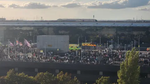 Junior Jones Large crowd of passengers gathered outside Heathrow Terminal 4 alongside multiple ambulances and emergency vehicles, after the building was evacuated during a safety incident.