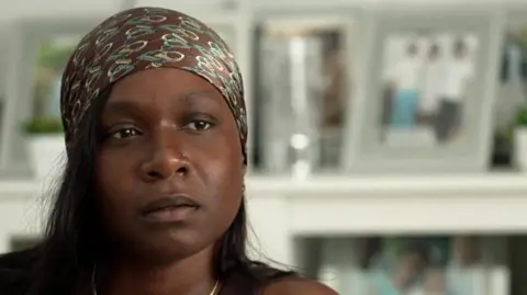 Close-up of Jodian Taylor wearing a patterned headscarf, looking slightly off camera during an interview.