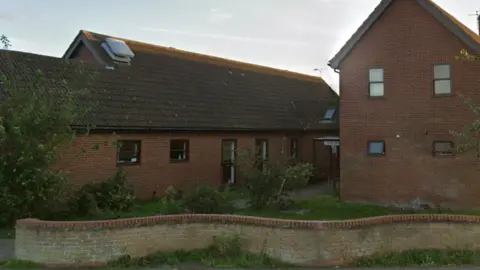 The outside of the Fyffe Centre in Lowestoft. It is a brick building with a curved brick fence at the front and trees on either side. 