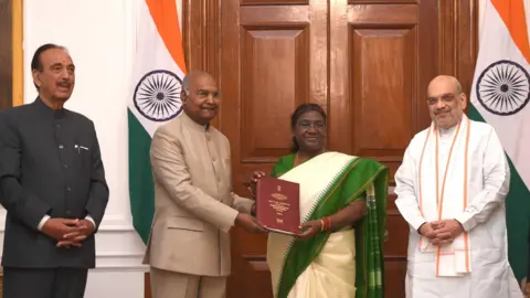 X/Presiden India Mantan Presiden Ramnath Kovind (kedua dari kiri) menyampaikan laporan komite tingkat tinggi mengenai penyelenggaraan pemilu serentak kepada Presiden India Droupadi Murmu (kedua dari kanan). Pemimpin Kongres Ghulam Nabi Azad (kiri) dan Menteri Dalam Negeri Amit Shah (kanan) juga hadir.