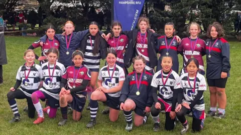 A team photo of the Vectis RFC girls team, with one row on their knees and another stood behind them.