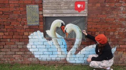 Artist with swan mural in Louth