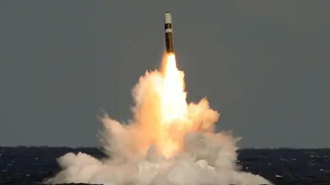 Undated handout photo of a still taken from video of the missile firing from HMS Vigilant, which fired an unarmed Trident II (D5) ballistic missile. A missile blasts above the ocean, with light and smoke behind it, over the ocean. 