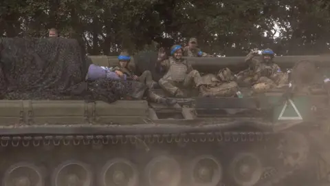 Getty Images Ukrainian soldiers sit on an armoured vehicle near the Russian border