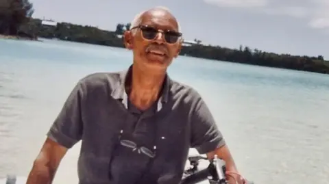 Nadine Gowan Foto handout keluarga Charles Todd, mengenakan kacamata hitam dan melihat ke atas ke arah matahari, dengan latar belakang air biru Aqua yang menakjubkan.