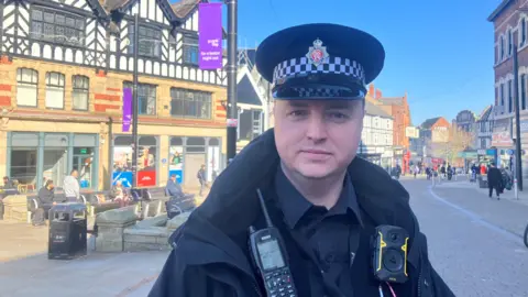 Photograph of Jonathan Calder from Greater Manchester Police. The neighbourhood police sergeant is pictured in Wigan town centre.
