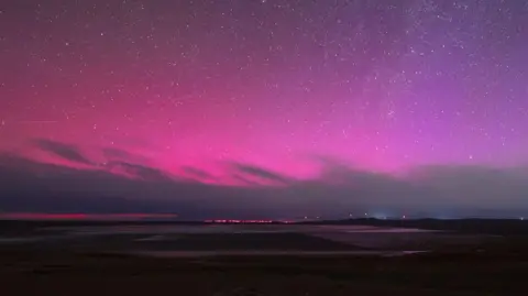 Getty Images Stars shine against a bright pink and purple night sky