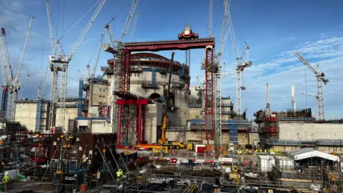 Hinkley Point C site with large part-built buildings and several cranes in position to move parts of the site.