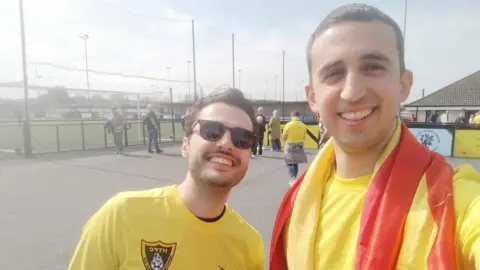 Supplied image of Alvaro Sanz with another man, both wearing yellow football shirts