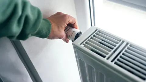 Getty Images A hand turning a knob on a radiator 