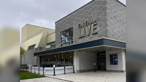 Fareham Live Outside the theatre of Fareham Live - grey, white and blue building with the words Fareham Live written in gold.