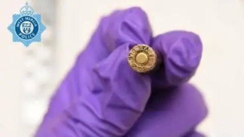 West Mercia Police A close-up of ammunition held by a person wearing a purple glove. The photograph, taken by police, has the force logo on it.