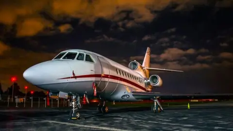 Getty Images  Falcon 900B business jet standing on the tarmac at an airport at night