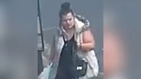 A blurry CCTV image of a woman carrying a bag