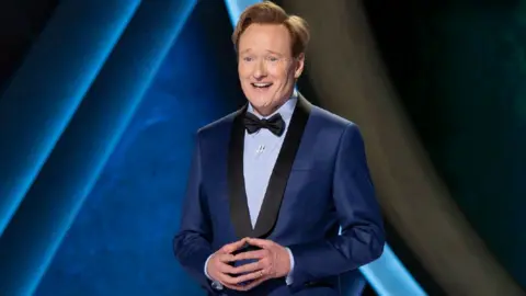 Getty Images Conan O'Brien wearing a blue suit on stage at the Dolby Theatre in Los Angeles in 2025