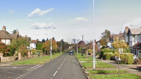 Image of Raeburn Avenue, a wide street lined with detached houses and some trees