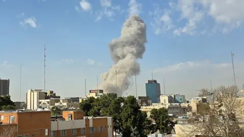Smokes rises into the blue sky from an apparent strike on Tehran