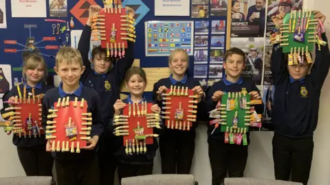 Salisbury Sea Cadets Six children holding cards with clothes pegs attached to sweets