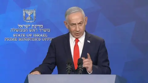 Netanyahu in front of a blue wall wearing a suit