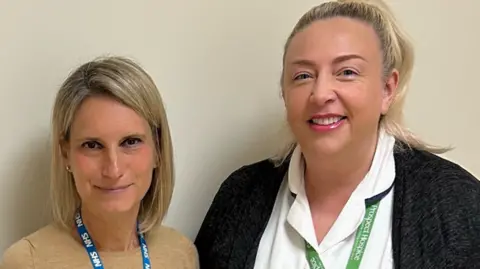 Dr Sara Mazzucco, from Great Western Hospital, and Dorinda Moffatt, from Prospect Hospice, stand together looking at the camera. Sara, on the left, has blonde hair and an NHS lanyard and Dorinda, on the right, has blonde hair tied on a ponytail and a prospect hospice lanyard.