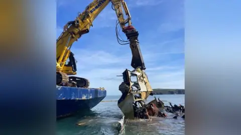 Steve Bradley A heavy piece of machinery is seen picking up pieces of the ship