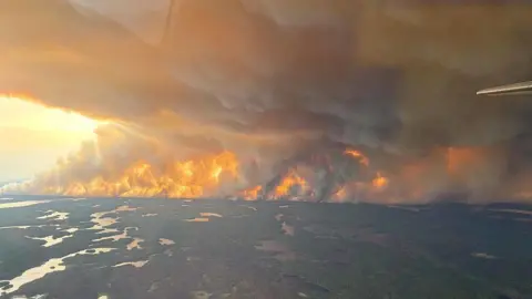 GOVERNMENT OF MANITOBA IN CANADA / HANDOUT An aerial view of a wildfire with large amounts of orange smoke rising from the earth
