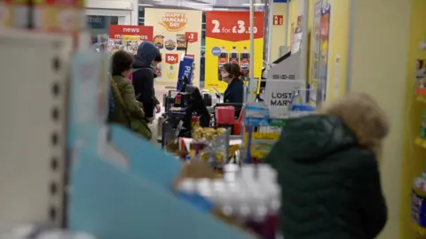 Female member of staff serving customers in a supermarket.