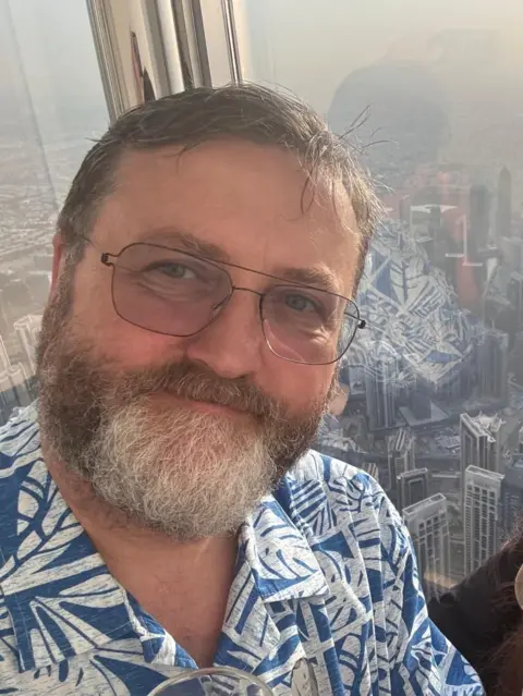 Paul Page-Tickell A man stood inside a building overlooking a city skyline