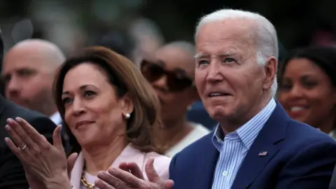 Reuters Joe Biden standing next to Kamala Harris - both of them are clapping and looking off into the distance 