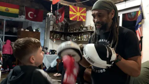 Dave Earle and a student holding boxing gloves and pads sparring together.