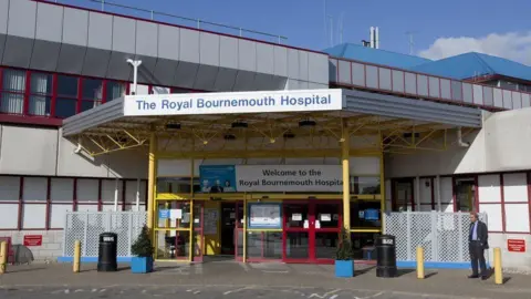 The main entrance to Royal Bournemouth Hospital, a modern, grey building with sliding glass doors