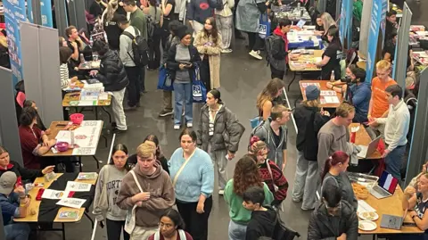 Students in a fresher' fair milling through stands 