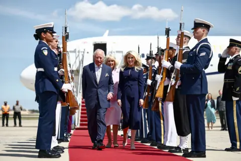 AFP via Getty Images Britain's King Charles III and Queen Camilla are greeted by US Protocol Chief Monica Crowley as they arrive at Joint Base Andrews, Maryland, on April 27, 2026.