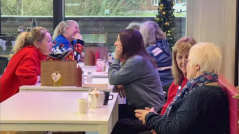 A photo of seven women sat at three tables drinking coffee