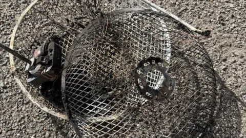 Essex County Fire and Rescue Service A metal electric fan that is blackened after a fire. It is placed on a grey carpet.